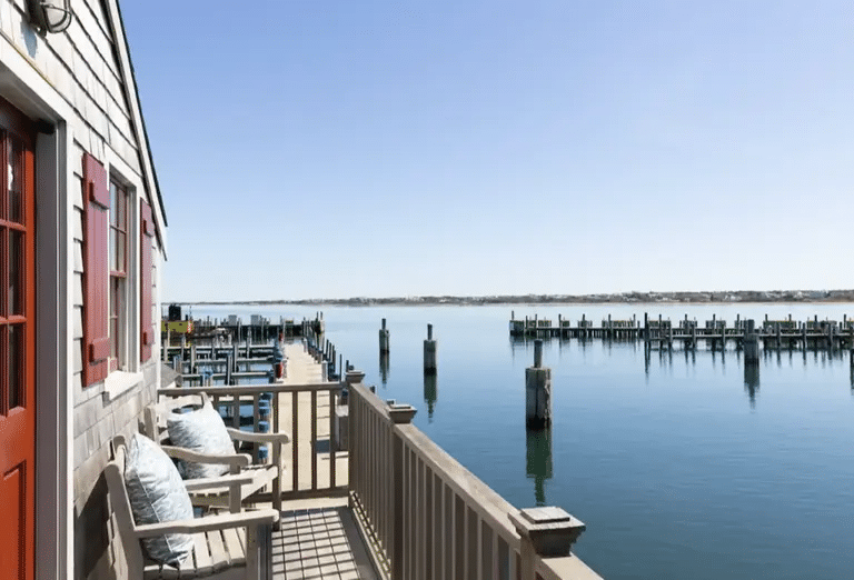 View from a patio at one of the Cottages at Nantucket, looking out onto the water with a bright red door and window seals.