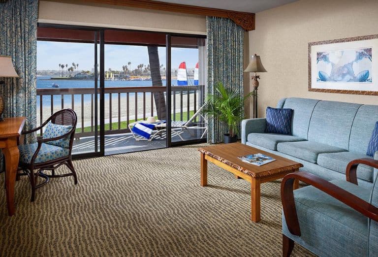 A hotel room with blue and wood decor overlooking water
