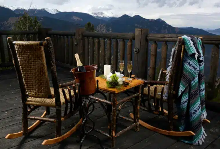 Rocking chairs on an overlook deck with a champagne setup, facing a mountain view