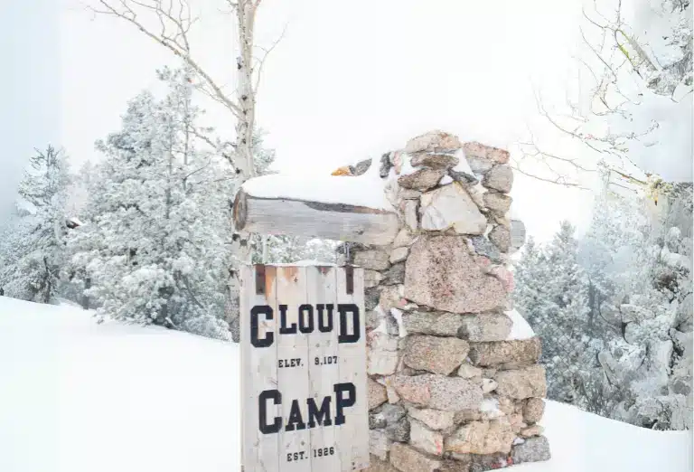 Entrance sign to Cloud Camp with snow-covered trees in the background.