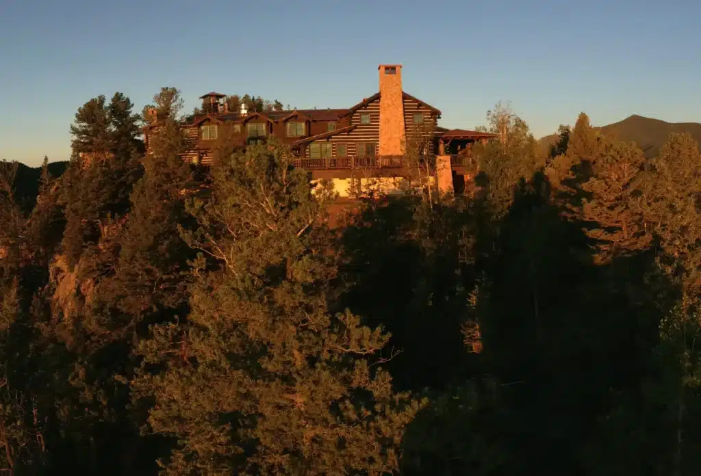 Secluded lodge atop a forested ridge at dusk with warm sunlight bathing its facade