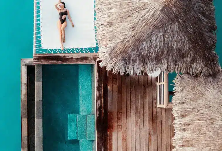 Overhead view of a person lounging on a hammock above a private deck with a plunge pool at the Four Seasons Bora Bora, capturing the essence of relaxation and luxury.