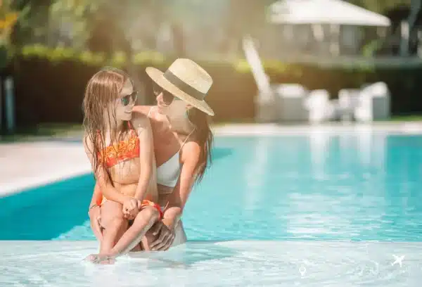 Mother and daughter enjoying time together in a pool at one of the best resorts for families, with the mother wearing a straw hat and both smiling