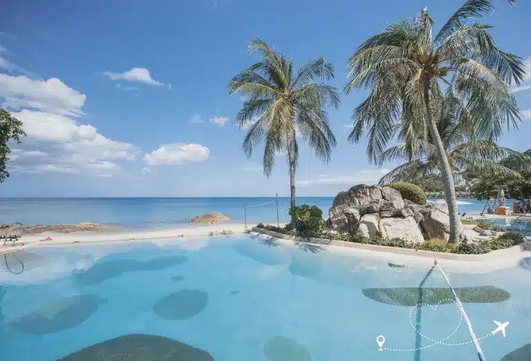 Sheraton Samui Resort pool with palm trees and a beach view, overlooking a serene ocean under a clear sky in Thailand.