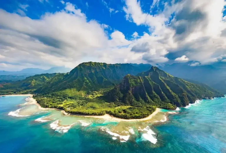 Aerial view of a Hawaiian island with lush mountains, turquoise waters, and sandy beaches.