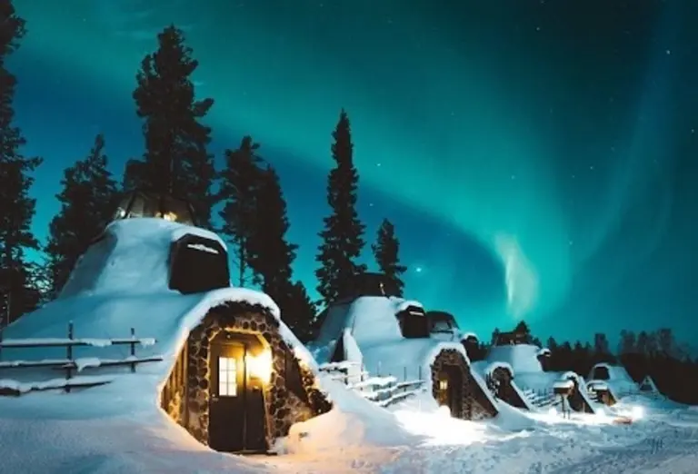 Snow-covered igloo-style cabins at Apukka Resort in Finland under the Northern Lights – an upscale hotel experience on Journey Beyond Aspen.