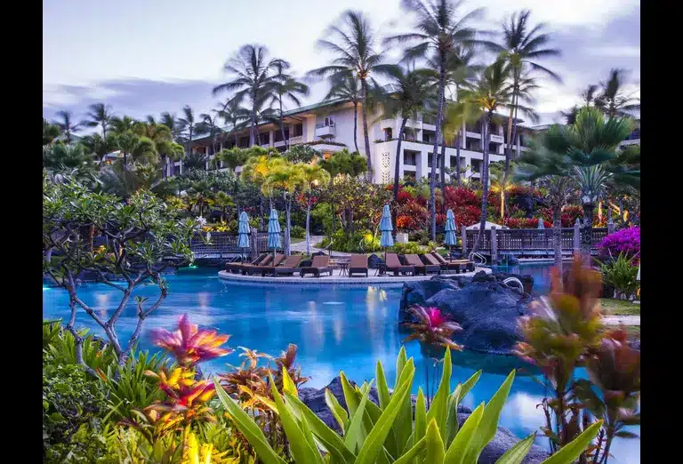 Tropical pool area with lounge chairs and lush greenery at the Grand Hyatt Kauai in Hawaii.