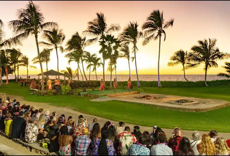 Visitors watching a traditional Hawaiian luau at sunset on the Paradise Cove Luau grounds in Oahu, Hawaii.